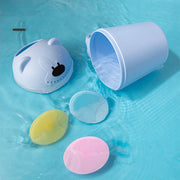 Colorful silicone baby shampoo brushes with soft bristles and a blue water-resistant bear-shaped container on a blue surface