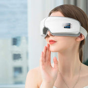 Woman using white eye massager for relaxing and reducing eye strain with vibration and heat therapy