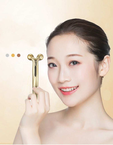 Woman holding gold 3D face-lifting device manual roller massager for skin firming and rejuvenation