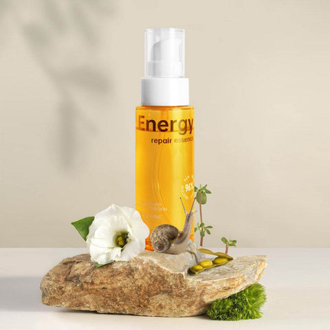 Snail Mucin Energy Repair serum bottle on rock with flower and snail, skin rejuvenation and hydration product