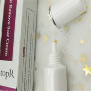 Skin repair cream tube with open cap and packaging box on white surface with gold star decorations