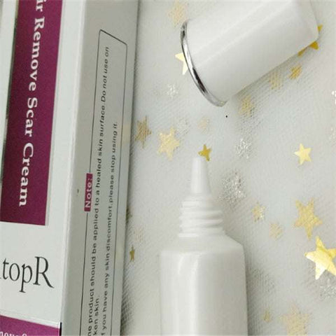Skin repair cream tube with open cap and packaging box on white surface with gold star decorations
